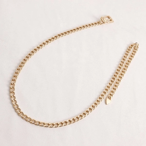 Detail of a polished gold Cuban link body chain featuring a buckle and teardrop charm