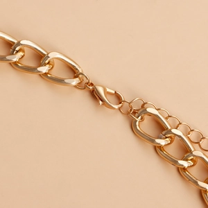 Detail of gold metal chunky chain waist belt featuring lobster clasp and extension link