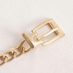 Macro shot of gold-plated metal buckle and thick chain detail on minimalist body chain