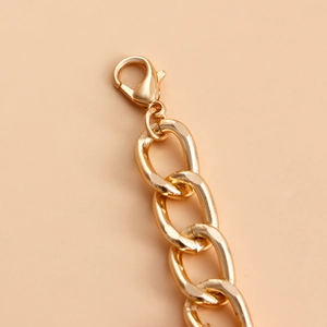 Detailed close-up of golden chunky chain link with a polished lobster clasp closure