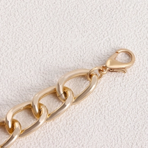 Macro detail of gold chunky chain with lobster clasp and polished metallic finish