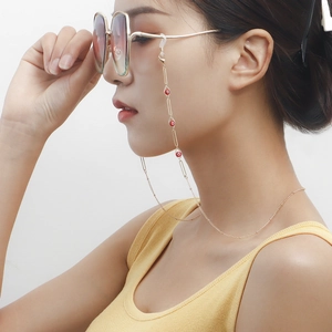 Close-up of golden Evil Eye glasses chain with colorful beads on sunglasses