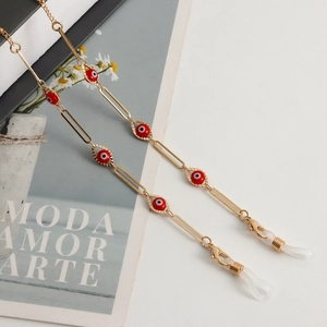 Detail of golden metal eyewear chain with red evil eye charms and silicone loops