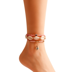 Detail of bohemian three-piece anklet set with natural shells and pink evil eye beads