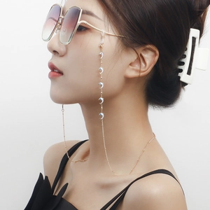 Détail d'une chaîne à lunettes dorée avec pendentifs dauphins bleus sur des lunettes