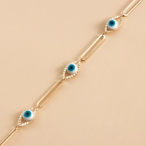Close-up of golden paperclip eyewear chain featuring blue evil eye charms and engravings