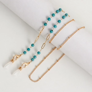 Détail de la chaîne de lunettes dorée avec perles turquoises et pendentifs dauphins