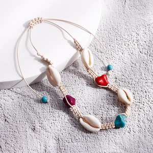 Dettaglio della collana di conchiglie intrecciata con turchese e cuore rosso