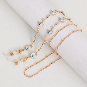 Détail de la chaîne de lunettes dorée avec pendentifs dauphins blancs et perles mauvais œil