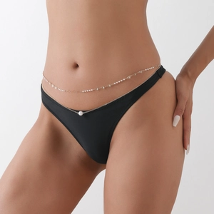 Détail d'une chaîne de corps dorée à double rangée avec petites perles et pendentif coeur
