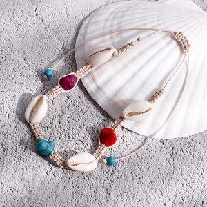 Dettaglio di una cavigliera boho fatta a mano con conchiglie naturali e pietre colorate