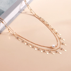 Détails macro d'une double chaîne dorée avec strass et paillettes en forme de gouttelette
