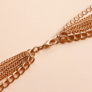 Detailed close-up of multi-layer gold metal body chain featuring a secure lobster clasp