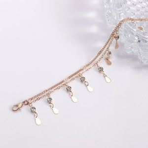 Détail de la chaîne de corps dorée avec strass scintillants et pendentifs en goutte d'eau