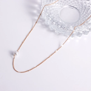 Détail d'une chaîne de taille dorée minimaliste avec un accent de perle blanche