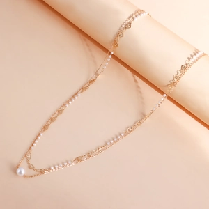 Détail de la chaîne de taille dorée avec perles et breloques en cœur évidées