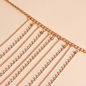 Detailed close-up of golden fringe body chain with sparkling rhinestones and metal layers