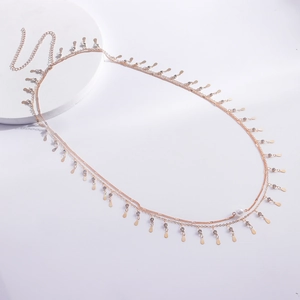 Détail de la chaîne de corps dorée avec gouttes de strass et accent de perle centrale