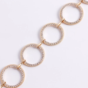 Dettaglio della catena da vita dorata con maglie circolari con pavé di cristalli bianchi