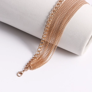 Detail of rose gold multi-layer metal body chain with lobster clasp on white display