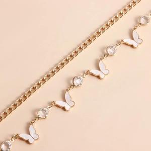 Detail of gold chain belt featuring white butterfly charms and sparkling crystal accents