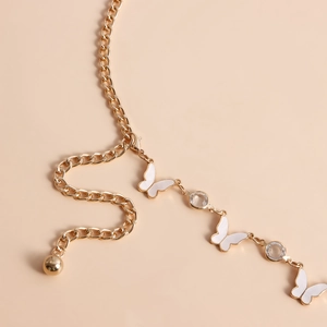 Detailed close-up of golden metal waist chain featuring white butterfly pendants and crystals