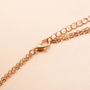 Detail of golden double-layer body chain featuring a lobster clasp and adjustable tail link