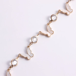 Detail of golden chain body jewelry with mother of pearl butterfly and sparkling crystals