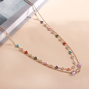 Detail of double-layered gold necklace featuring colorful heart charms and clear crystals