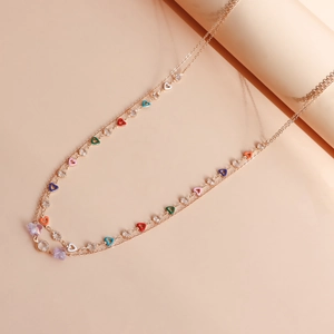 Detail of double-layer gold chain necklace with colorful heart beads and purple butterflies