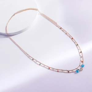 Detail of layered gold body chain featuring blue butterfly charms and colorful bead accents