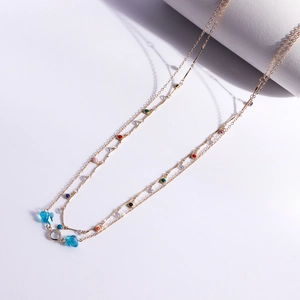 Detail of double-layer gold chain with colorful beads and sky blue butterfly charms