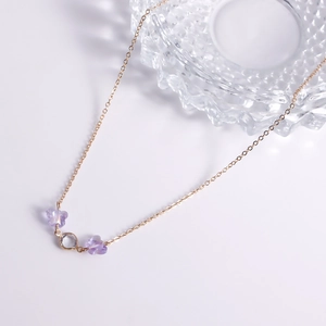 Detail of golden necklace with purple butterfly beads and a clear crystal pendant