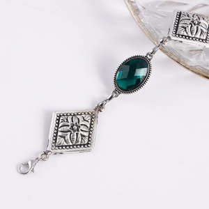 Dettaglio di un bracciale in argento vintage con gemma verde e placche metalliche incise
