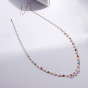 Detail of gold body chain featuring multi-colored heart charms and sparkling crystals