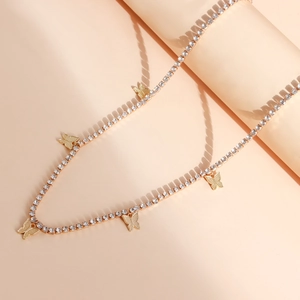 Collana a farfalla dorata con strass scintillanti su una catena stile tennis