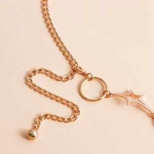 Detail shot of golden starfish body chain featuring crystal star and bold metal rings