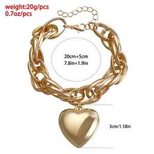 Detail of chunky gold chain bracelet with a large hollow heart pendant and lobster clasp