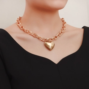 Close-up of chunky gold-tone link chain necklace with a 3D heart pendant on a model