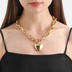 Close-up of a chunky gold O-chain necklace with a large polished heart pendant on model
