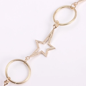 Detail of gold starfish charm with textured surface and sleek rings on body chain