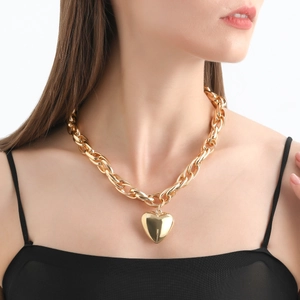 Macro detail of glossy gold heart pendant and thick oval link chain necklace
