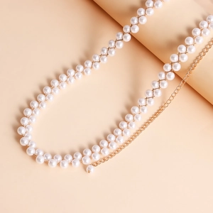 Dettaglio catena corpo in perle intrecciate con maglie dorate su sfondo rosa