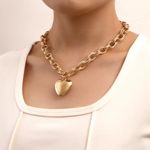 Detail of chunky gold chain choker with large heart pendant on model's neck