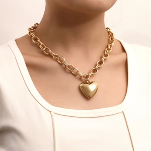 Chunky gold chain necklace featuring a large heart pendant worn by a female model