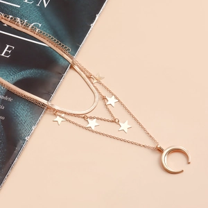 Dettaglio della collana a strati in oro rosa con catena a serpente e ciondoli luna stelle