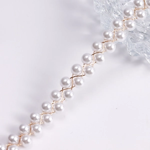 Dettaglio della catena da corpo intrecciata con perle bianche e fili metallici dorati