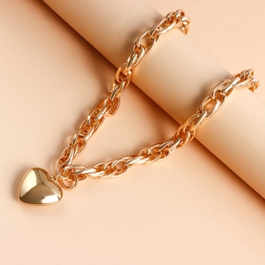 Detailed close-up of a polished gold heart pendant on a chunky O-chain necklace