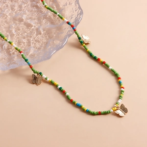 Bohemian colorful seed bead body chain with gold butterfly charms on a glass tray