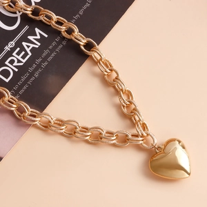 Detail of chunky gold chain necklace featuring a large polished heart pendant